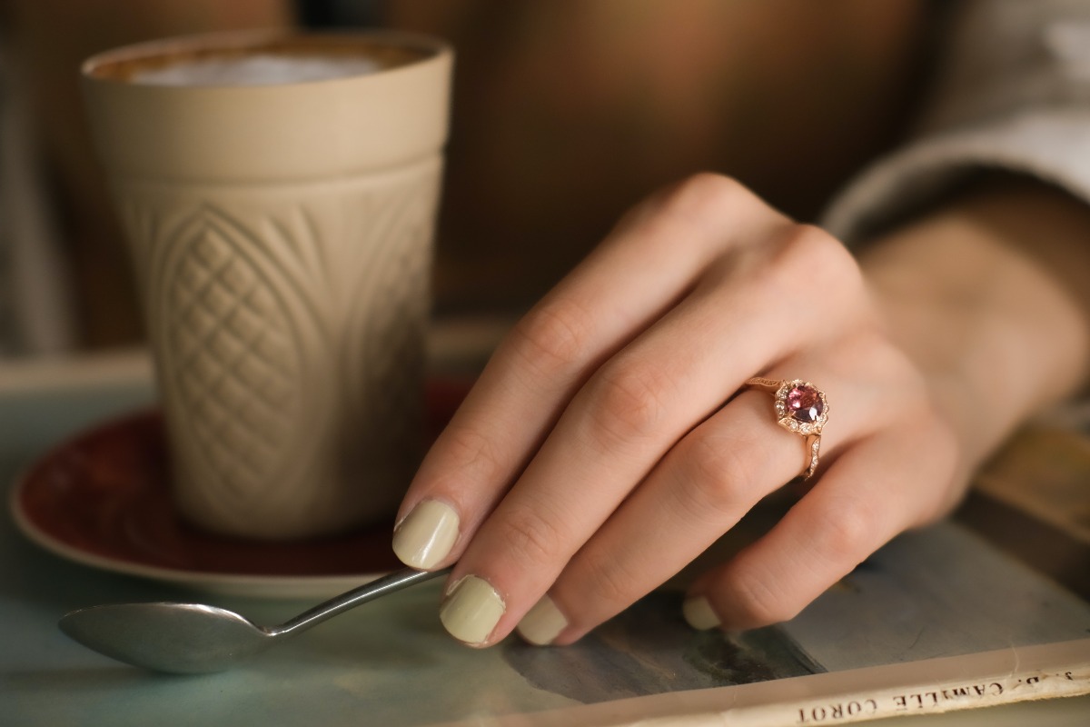 a coffee mug and a women's hand with a ruby ring